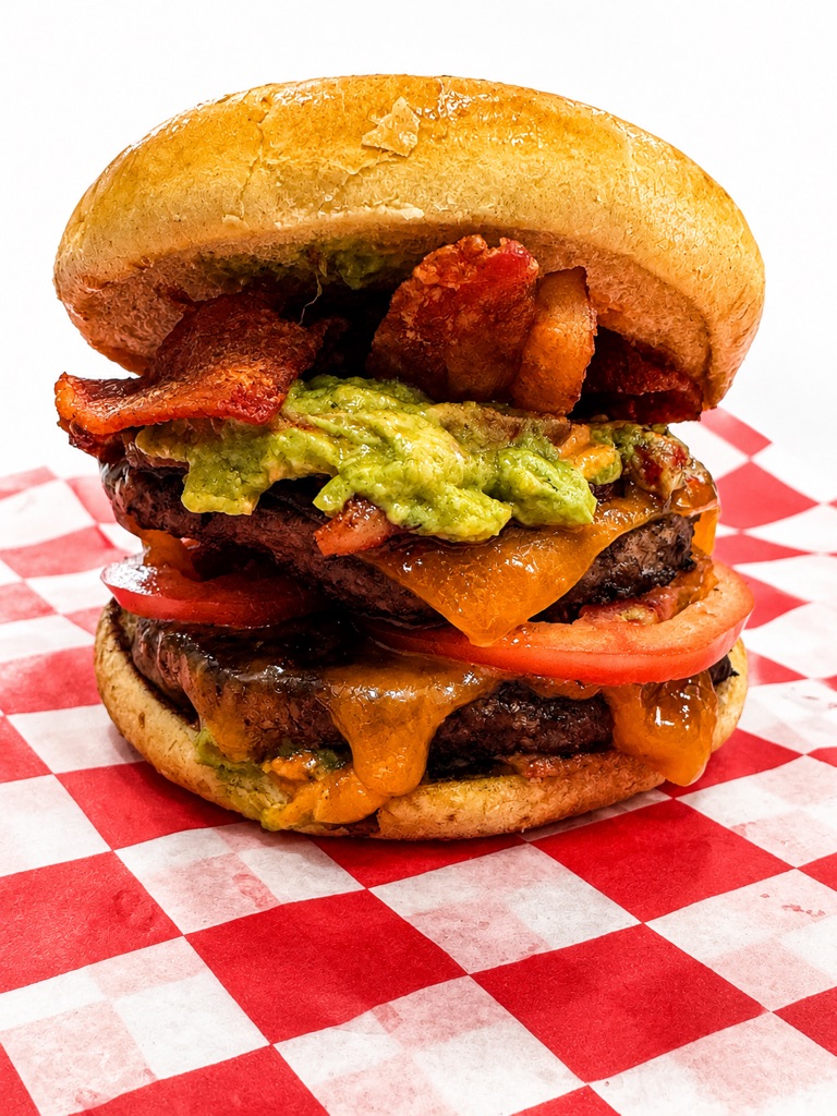Double cheeseburger stacked with guacamole, bacon and tomato