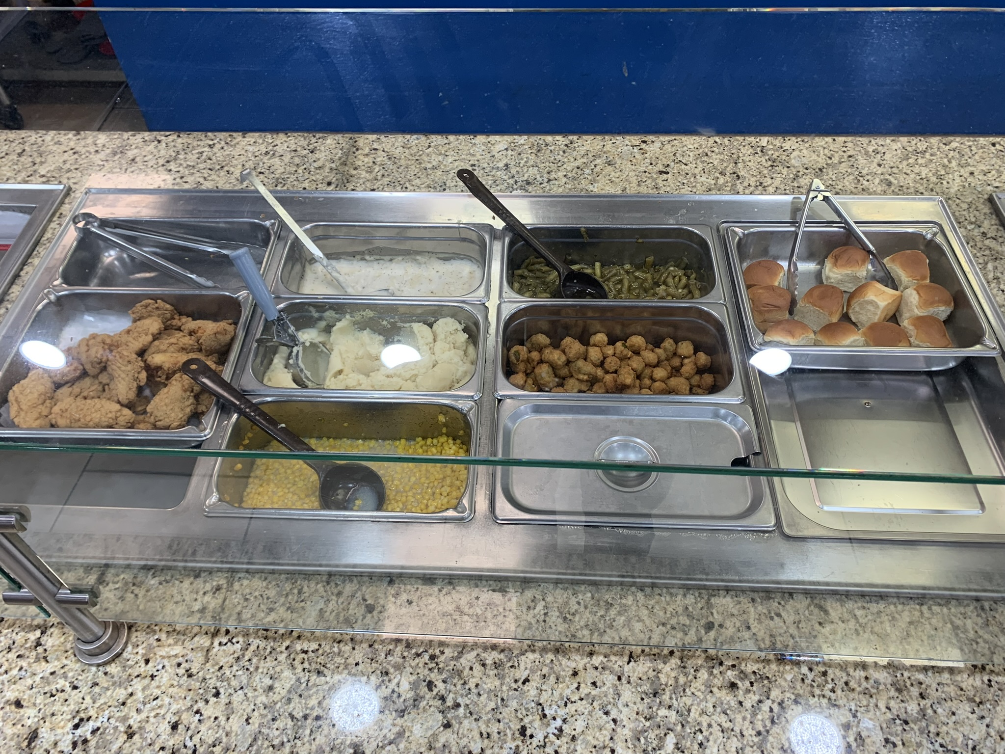 Hot food bar with fried chicken, sides, and fresh rolls